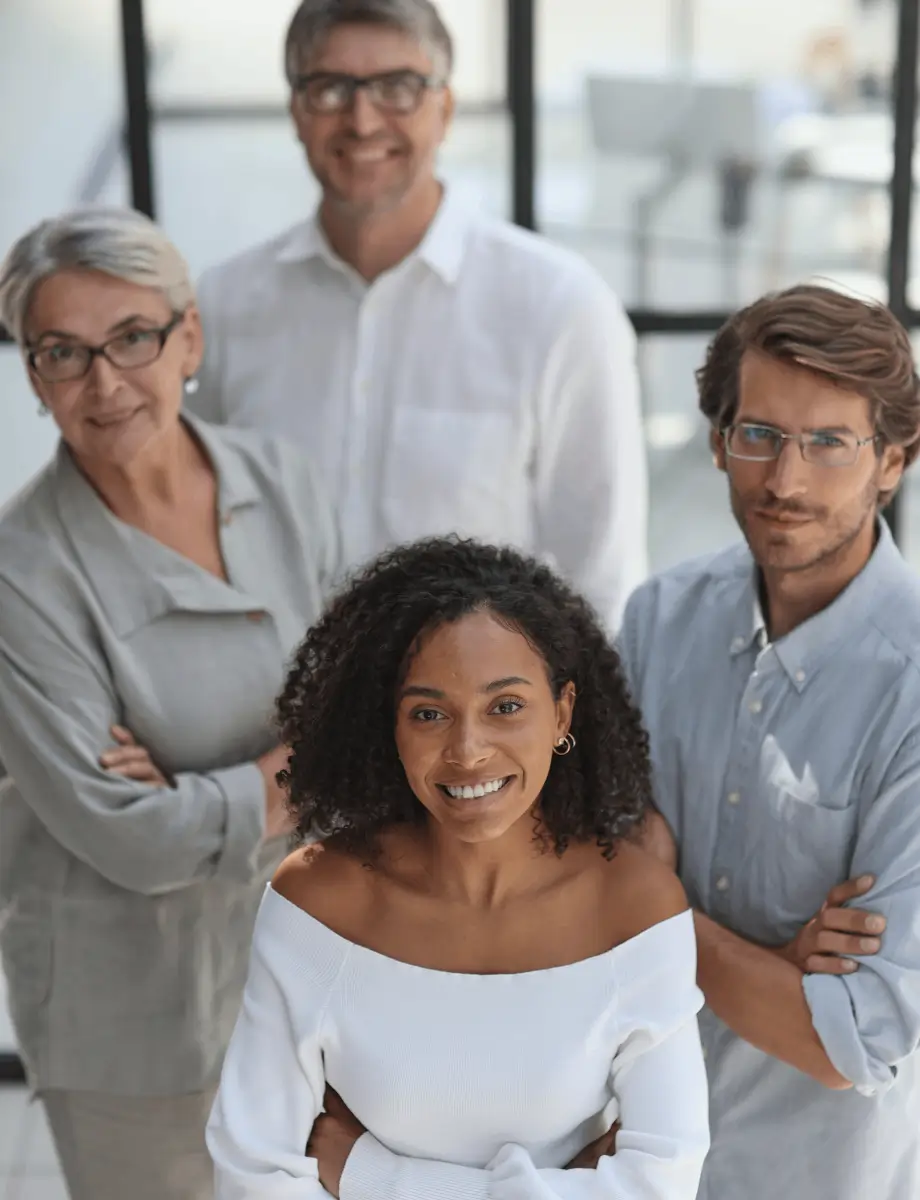 A diverse group of four professionals standing together, smiling confidently with their arms crossed.