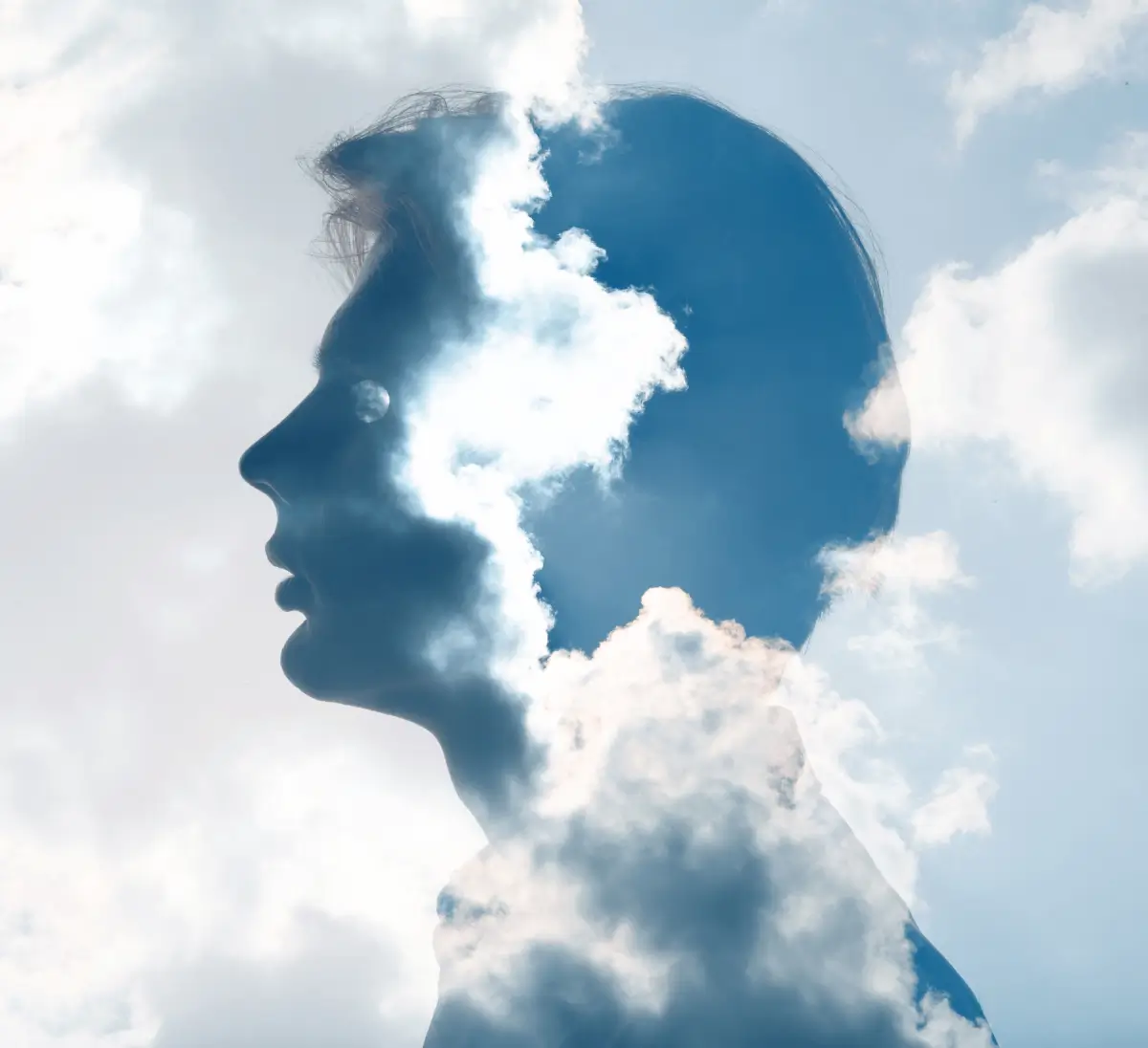 Double exposure image of a male head silhouette blended with clouds and sky, symbolizing thought and mental state.